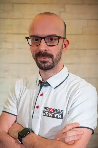 Homme avec lunettes et polo blanc, bras croisés.